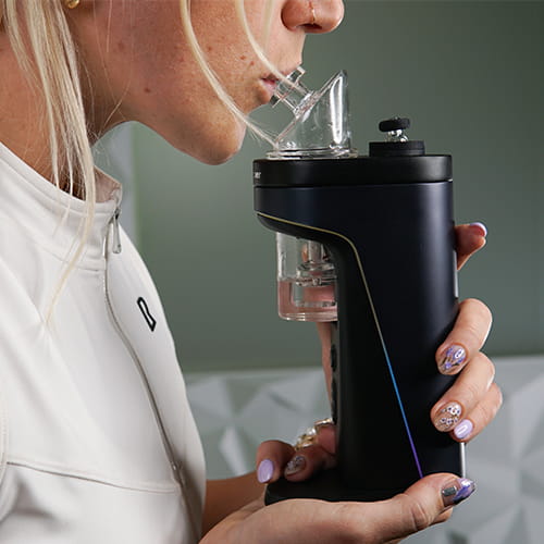 Woman inhaling from Dr. Dabber Switch 2's glass bubbler