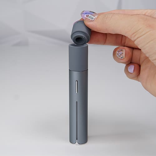 Puffco Pivot is on a table while a woman is attaching its extended mouthpiece.