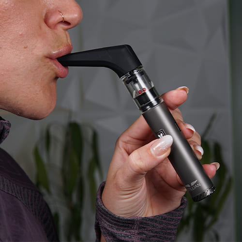 Woman inhaling from utillian 6 dab pen withe extended mouthpiece
