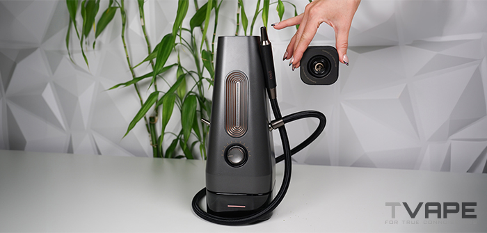 Hand lifting the removable Glass ThermoCap off the AirVape Enso 2026 electric shisha, showing the open heating chamber and attached vapor hose